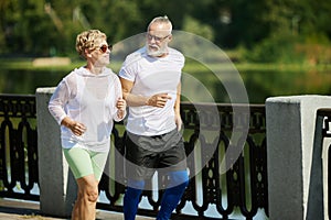 Beautiful couple, mature people, man and woman jogging, running on early morning outdoors. Training together