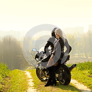 Beautiful couple with a motorcycle at sunset.