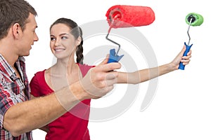 Beautiful couple painting wall and smiling.