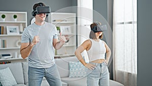 Beautiful couple playing dancing video game using virtual reality glasses at home