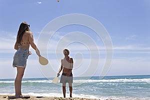 Beautiful couple playing paddle on the beach