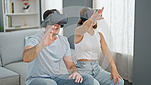 Beautiful couple playing video game using virtual reality glasses at home