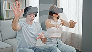 Beautiful couple playing video game using virtual reality glasses at home