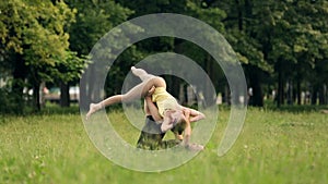 Beautiful couple practicing acro yoga. Young yoga instructors practice in a city park on green grass. Two successful