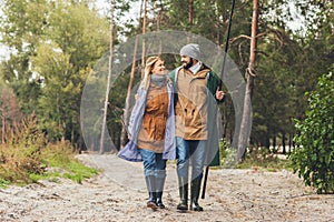 beautiful couple in raincoats with rods going