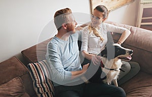 Beautiful couple relaxing at home and loving their dog