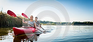 Beautiful couple sailing kayak on lake