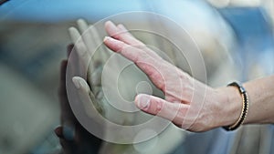 Beautiful couple saying goodbye with hands on window car at street