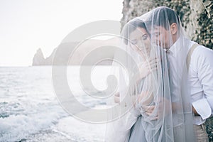 Beautiful couple on the seafront closed in a veil, laughing, smiling, happy, Wedding day, love