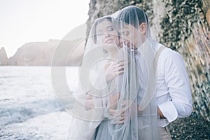 Beautiful couple on the seafront closed in a veil, laughing, smiling, happy, Wedding day, love