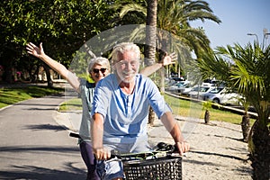 Beautiful couple of senior and mature married, riding a doble bike, tandem, together to have fun with a great and sunny day -