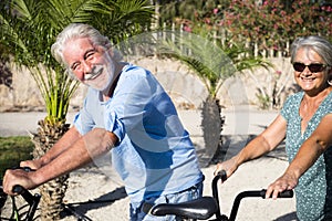 Beautiful couple of senior and mature married, riding a doble bike, tandem, together to have fun with a great and sunny day -