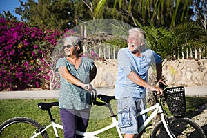 Beautiful couple of senior and mature married, riding a doble bike, tandem, together to have fun with a great and sunny day -