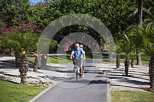 Beautiful couple of senior and mature married, riding a doble bike, tandem, together to have fun with a great and sunny day -