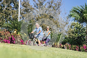 Beautiful couple of senior and mature married, riding a doble bike, tandem, together to have fun with a great and sunny day - woma