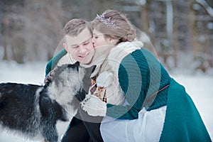 Beautiful couple with Siberian husky in snowy winter forest
