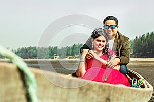 Beautiful couple sitting on rowboat at beach against sky