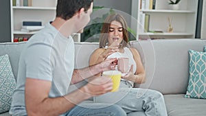 Beautiful couple sitting on sofa together drinking coffee smiling at home