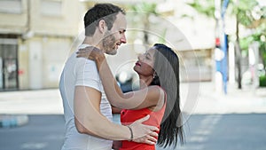 Beautiful couple smiling confident hugging each other dancing at street