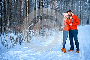 Beautiful couple standing arm in arm in the red sweater in the background of the forest in winter , a walk in the winter woods