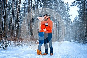 Beautiful couple standing arm in arm in the red sweater in the background of the forest in winter , a walk in the winter woods