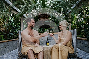 Beautiful couple standing hot tub, toasting, drinking champagne, enjoying romantic wellness weekend in spa. Concept