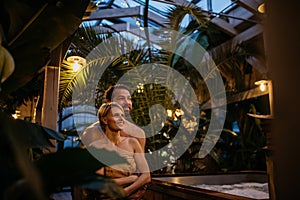 Beautiful couple standing in hotel greenhouse, enjoying romantic wellness weekend in spa. Concept of Valentine& x27;s Day