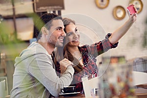 Beautiful couple taking selfie photo in cafe