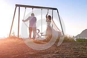 Beautiful couple together on swings at sunset.