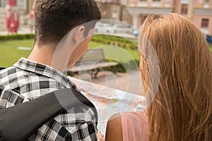 Beautiful couple of tourists holding a map in