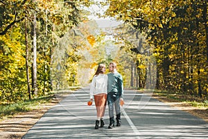 Beautiful couple walking on asphalt road in autumn colorful park