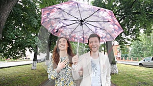 Beautiful couple walking under umbrella in park