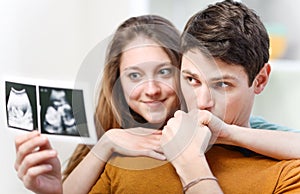 Beautiful couple watching with emotion ultrasound pictures of their baby