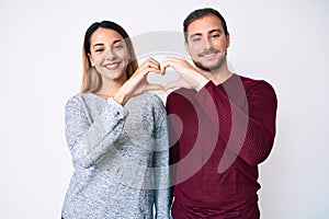 Beautiful couple wearing casual clothes smiling in love showing heart symbol and shape with hands