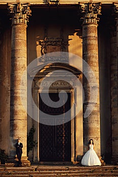Beautiful couple in wedding dress outdoors near the vintage portal entrance with columns