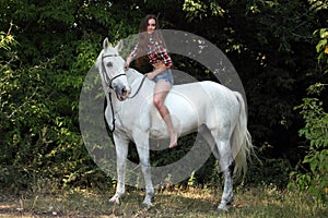 Beautiful cowgirl bareback ride her horse in forest glade at sunset