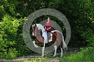 Beautiful cowgirl bareback ride her horse in woods glade