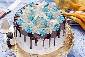 Beautiful cream cake decorated with chocolate leaks, cream and sugar snowflakes from mastic