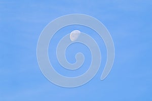 A beautiful crescent moon in daylight against a clear blue sky