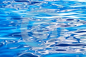 Beautiful crincled reflections on bright blue sea water with different shades. Abstract water background