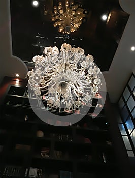 Beautiful crystal chandelier hanging to the mirror reflective ce