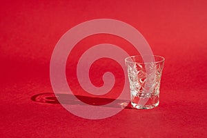 Beautiful crystal glasse with shadows on a bright red background, close-up