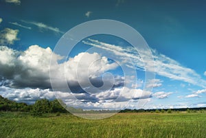 Beautiful cumulus clouds over meadows and fields in the valley