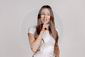 Beautiful cunning woman smiling, showing gesture secret sign with finger near her lips.