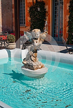 Beautiful cupid sculpture fountain in the garden of Villa Cipressi, Varenna, Italy.