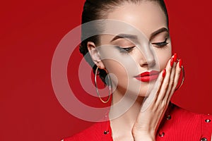 Beautiful curle hair female in red with red lips and dress manicure, beauty rose over red background