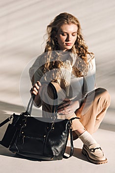 beautiful curly blond hair woman posing with a small shopper bag sitting on the floor