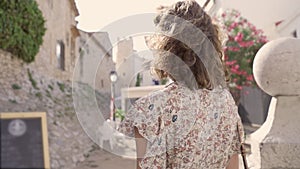 Beautiful curly brunette tourist in the Mediterranean village of Sitges on the bakground