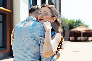 Beautiful curly dark-haired wife hugging her supportive man