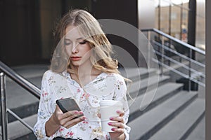 Beautiful curly hair girl holding phone and a cup of coffee